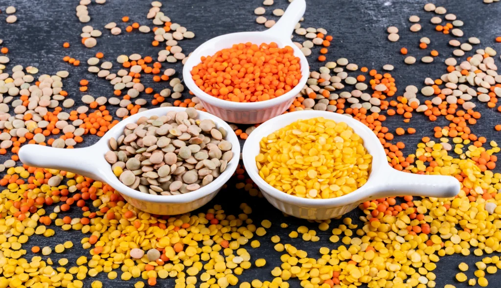 different-lentils-mini-white-spice-bowls-black-stone-table-side-view