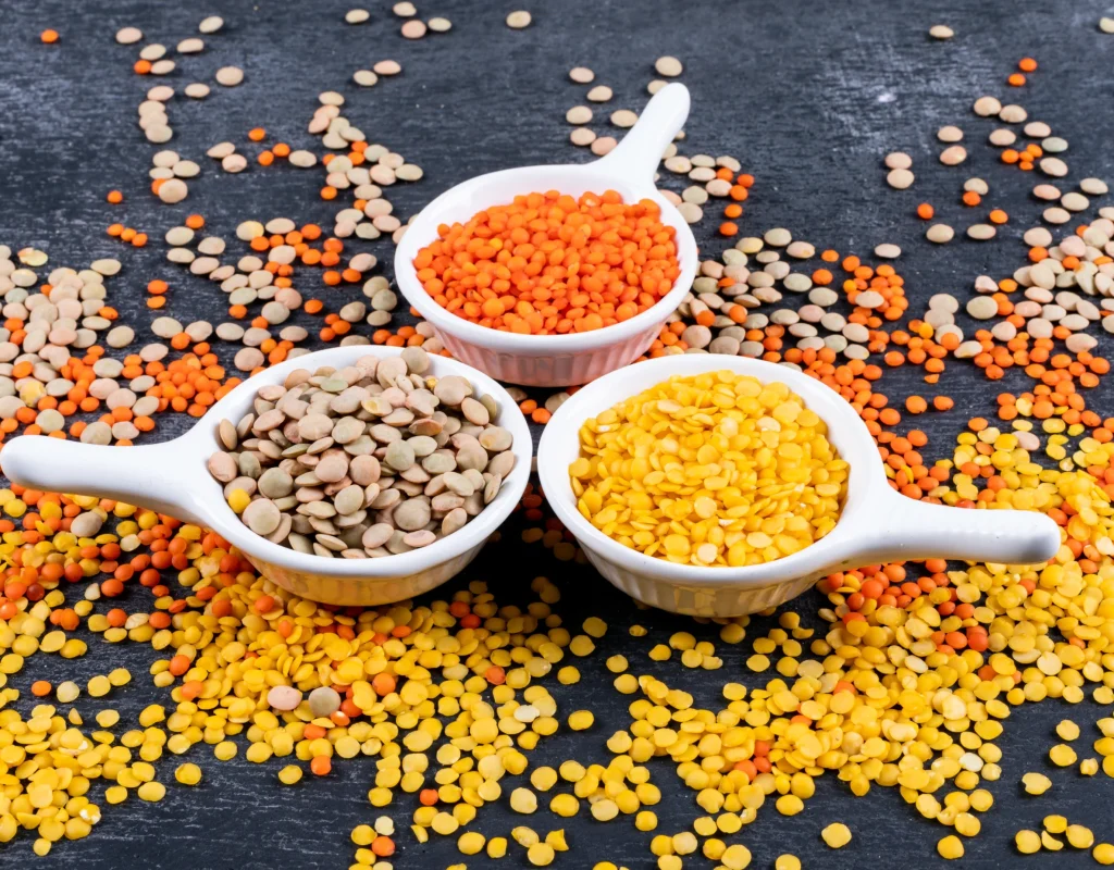 different-lentils-mini-white-spice-bowls-black-stone-table-side-view